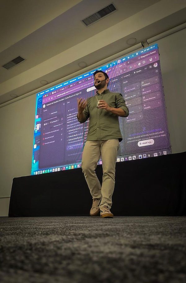 Ángel Molina en el escenario durante una conferencia de inteligencia artificial en Costa Rica, con la presentación proyectada al fondo