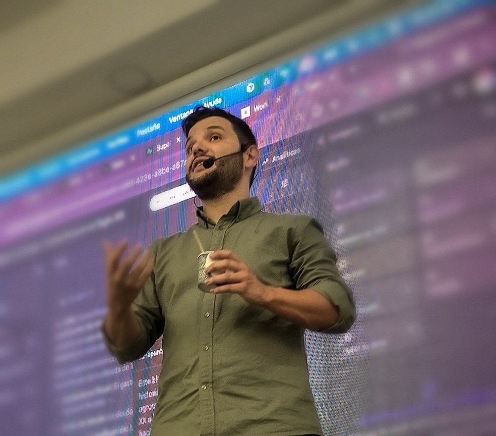 Ángel Molina, speaker internacional de inteligencia artificial, en el escenario durante una ponencia, con una pantalla gigante detrás mostrando una demostración de IA en directo