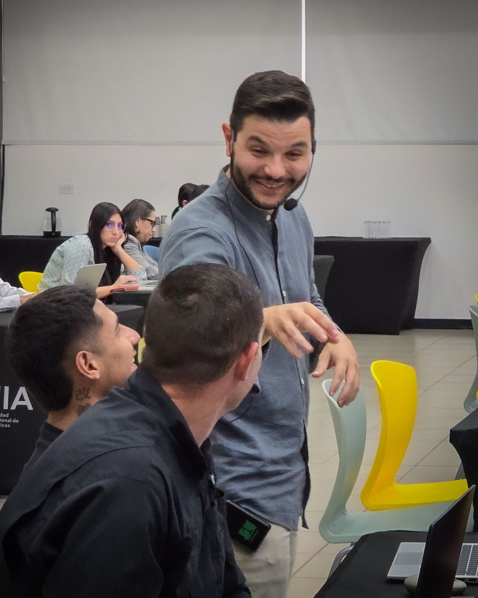 Ángel Molina, speaker internacional de inteligencia artificial, sonriendo con dos asistentes durante un taller en la Universidad Internacional de las Américas, Costa Rica
