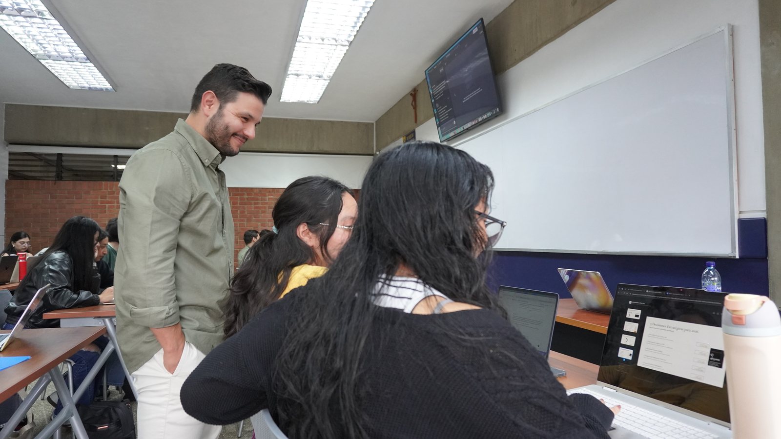 Ángel Molina acompañando a dos alumnas con su portátil durante el taller de agentes de IA en la Universidad del Valle de Guatemala, Ciudad de Guatemala, 17 de agosto de 2026